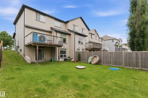Expansive rear yard featuring green lawn, privacy fencing, and a raised wood deck - 1608 65 Street Sw, Edmonton, AB - Outdoor With Deck Patio Veranda