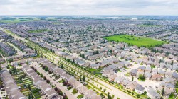 Expansive residential development featuring numerous single-family homes, tree-lined streets, and open green spaces - 
