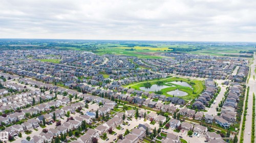 Aerial perspective of a developed residential area featuring numerous single-family homes, a central park with two ponds, and paved roads - 1608 65 Street Sw, Edmonton, AB - Outdoor With View