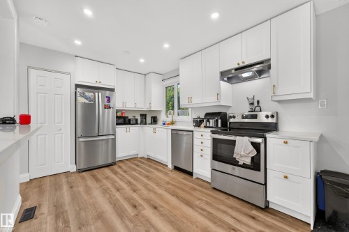 Kitchen featuring wood-finish flooring, white cabinetry, stainless steel appliances, and recessed lighting - 2412 80 Street Nw, Edmonton, AB 
