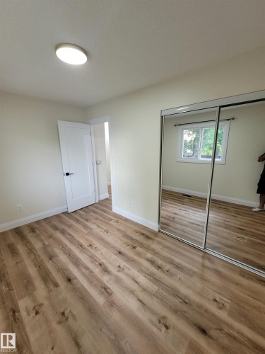Wood-finish flooring, white walls, white doors, and a ceiling-mounted light fixture - 2412 80 Street Nw, Edmonton, AB 