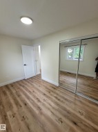 Wood-finish flooring, white walls, white doors, and a ceiling-mounted light fixture - 