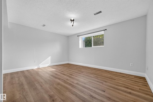 Wood-finish flooring, white walls, and a window with a black curtain rod - 2412 80 Street Nw, Edmonton, AB 