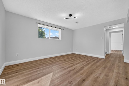 Recessed window with white trim, wood-finish flooring, light gray wall paint, and a contemporary ceiling light fixture - 2412 80 Street Nw, Edmonton, AB 