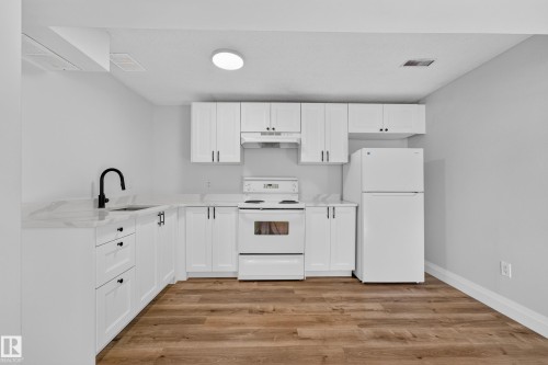 Kitchen featuring white cabinetry, light countertops, wood-finish flooring, and white appliances - 2412 80 Street Nw, Edmonton, AB 