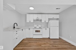 Kitchen featuring white cabinetry, light countertops, wood-finish flooring, and white appliances - 