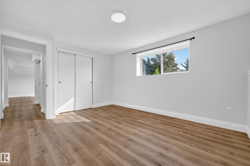 Wood-finish flooring throughout, white interior walls, and a window with exterior tree scenery - 2412 80 Street Nw, Edmonton, AB 