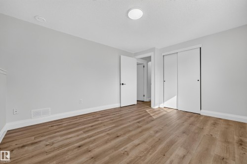 Wood-finish flooring, white trim, sliding closet doors, and recessed ceiling lighting - 2412 80 Street Nw, Edmonton, AB 
