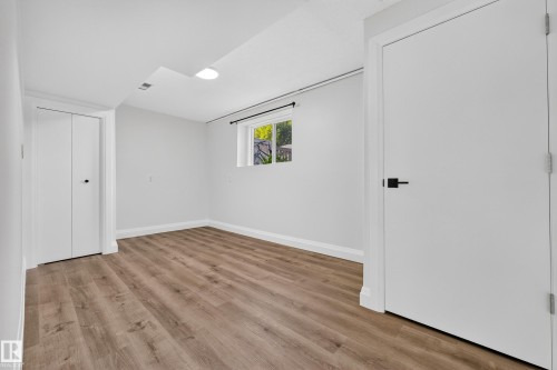 Wood-finish flooring, white walls, and a window providing natural light - 2412 80 Street Nw, Edmonton, AB 
