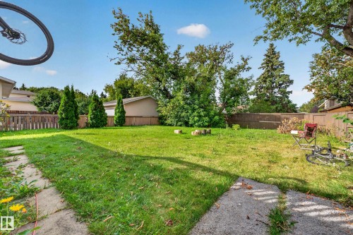 Expansive backyard featuring a lush lawn, mature trees, and privacy fencing - 2412 80 Street Nw, Edmonton, AB 
