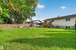 Expansive backyard featuring a large green lawn, wood fence, and a multi-level wood deck with stairs - 