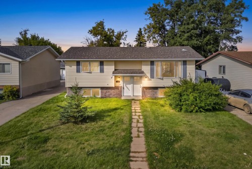 Two-story residence featuring light-colored siding, a dark shingle roof, and a stone facade - 2412 80 Street Nw, Edmonton, AB 