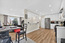 Kitchen with white cabinetry, stainless steel appliances, and wood-finish flooring - 
