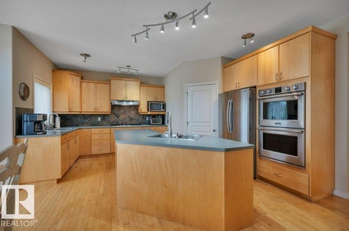 Kitchen featuring stainless steel appliances, a center island with sink, and track lighting - 739 Haliburton Crescent Nw, Edmonton, AB 