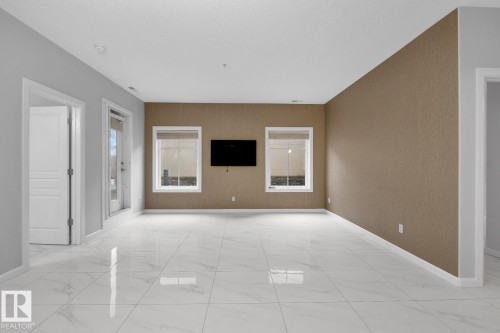 White tile flooring, white trim, textured accent wall, recessed lighting, and a white interior door - #105 160 Magrath Rd Nw, Edmonton, AB 