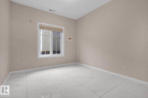White tile flooring, window with white trim, and neutral wall color - #105 160 Magrath Rd Nw, Edmonton, AB 
