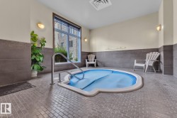 Indoor spa with a tiled surround, stainless steel grab rail, and large windows - 