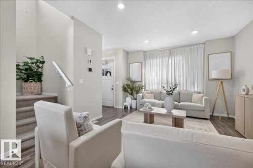 Recessed ceiling lighting, wood-finish flooring, staircase with carpeted treads, white interior door, and large window with vertical blinds - 2046 Chalmers Way Sw, Edmonton, AB 