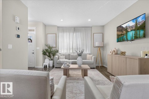Recessed ceiling lighting, full-height windows, wood-finish flooring, light neutral wall tones, and a built-in media console - 2046 Chalmers Way Sw, Edmonton, AB 