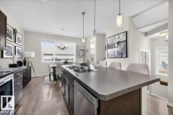 Kitchen featuring a large island with sink, wood-finish flooring, and pendant lighting - 