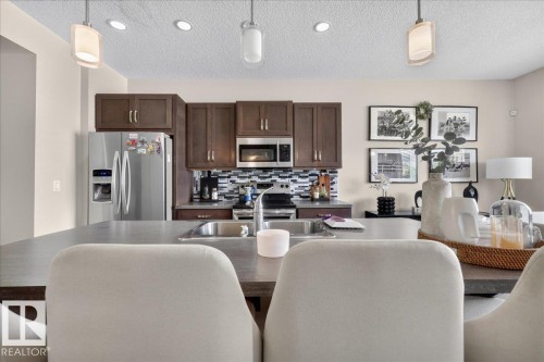 Kitchen featuring wood cabinetry, stainless steel appliances, a tile backsplash, and recessed lighting - 2046 Chalmers Way Sw, Edmonton, AB 