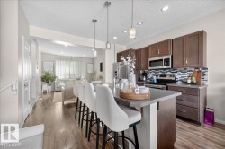 Expansive kitchen with wood-finish flooring, dark wood cabinetry, stainless steel appliances, and a tiled backsplash - 