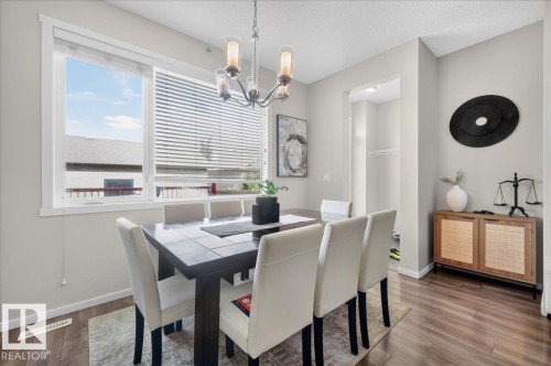 Wood-finish flooring with light-colored walls and a modern chandelier - 2046 Chalmers Way Sw, Edmonton, AB 