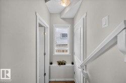 Hallway with wood-finish flooring, white trim, and a window with blinds - 