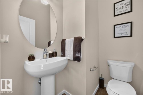 Pedestal sink with chrome-finish faucet, circular mirror, and neutral wall paint - 2046 Chalmers Way Sw, Edmonton, AB 