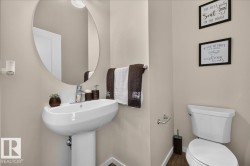 Pedestal sink with chrome-finish faucet, circular mirror, and neutral wall paint - 