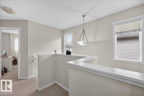 Neutral-toned walls with contrasting white trim, carpeted flooring, and a pendant light fixture - 2046 Chalmers Way Sw, Edmonton, AB 