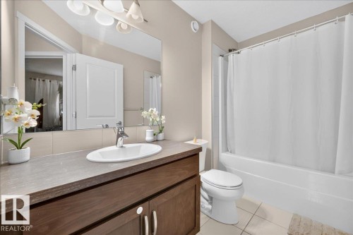 Vanity with an integrated sink, wood-finish cabinetry, and a countertop - 2046 Chalmers Way Sw, Edmonton, AB 