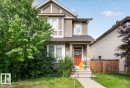 Two-story residence featuring horizontal siding, a red entry door, white trim, and a gabled roofline - 2046 Chalmers Way Sw, Edmonton, AB 