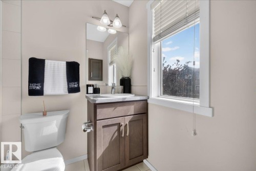 Vanity with built-in cabinetry, integrated sink, and wall-mounted mirror - 2046 Chalmers Way Sw, Edmonton, AB 