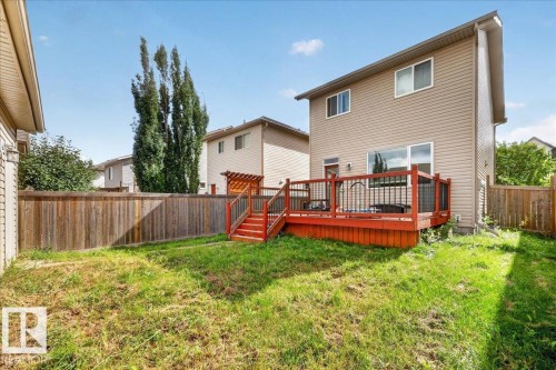Raised wood deck with red finish, black metal railings, and wood pergola - 2046 Chalmers Way Sw, Edmonton, AB 