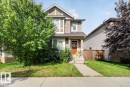 Two-story residence featuring light-toned siding with contrasting trim, a covered front porch, and a red entry door - 2046 Chalmers Way Sw, Edmonton, AB 
