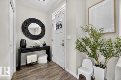 Wood-finish flooring, white paneled door with window, recessed lighting, and light-toned wall paint - 