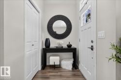 Entryway featuring wood-finish flooring, a white paneled door with glass inserts, and a built-in closet with bi-fold doors - 
