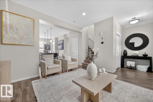 Wood-finish flooring throughout, light neutral wall tones, recessed lighting, staircase with closed risers, and built-in closet with panel door - 2046 Chalmers Way Sw, Edmonton, AB 