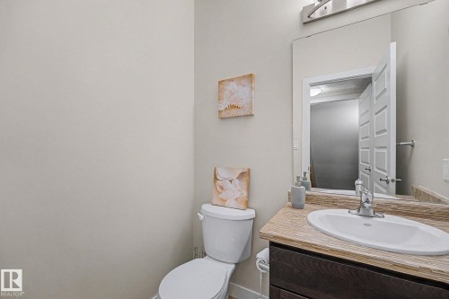 Bathroom vanity featuring a vessel sink, chrome faucet, wood-finish cabinetry, and a textured countertop - 3343 Weidle Way Sw, Edmonton, AB 