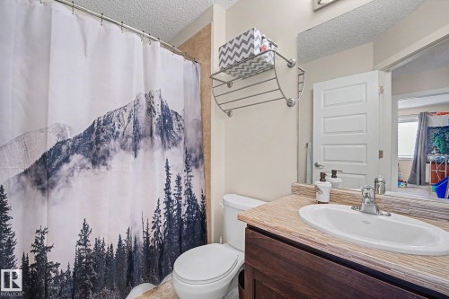 Bathroom featuring a dark wood-finish vanity with an integrated sink, chrome faucet, and a textured countertop - 3343 Weidle Way Sw, Edmonton, AB 