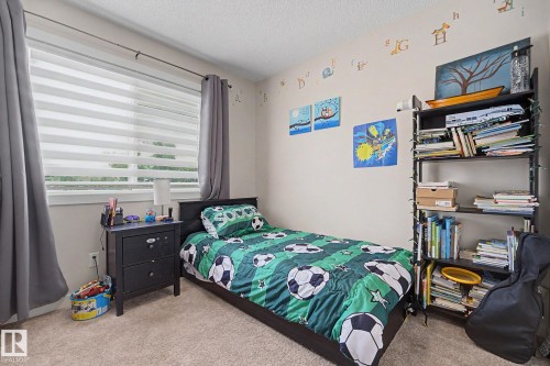 Carpeted bedroom featuring a large window with horizontal blinds and full-length gray drapes - 3343 Weidle Way Sw, Edmonton, AB 