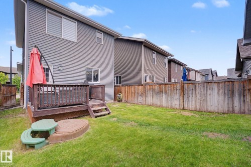 Expansive green lawn featuring a wooden privacy fence and a dark-stained wood deck with stairs - 3343 Weidle Way Sw, Edmonton, AB 
