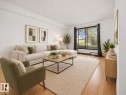 Hardwood flooring throughout, white walls, and a large sliding glass door with black trim - #119 3611 145 Av Nw, Edmonton, AB 