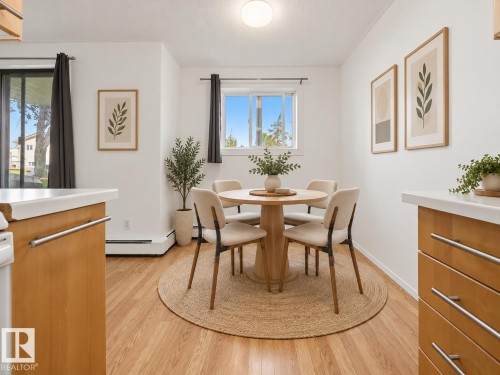 Light wood-finish flooring, white walls, built-in overhead lighting, and a white framed window - #119 3611 145 Av Nw, Edmonton, AB 