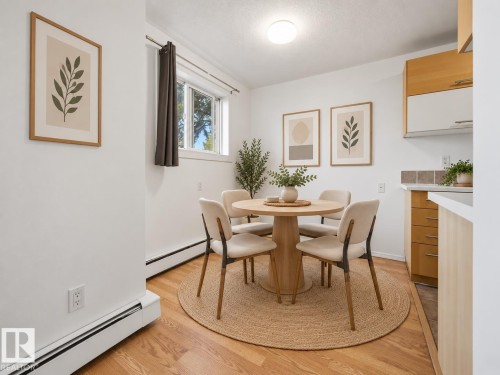 Wood-finish flooring, white walls, built-in baseboard heating, and a window with trim - #119 3611 145 Av Nw, Edmonton, AB 