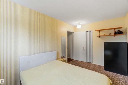 Striped wall covering, ceiling-mounted light fixture, wood shelving, and bi-fold closet doors - 9311 68 Street Nw, Edmonton, AB 