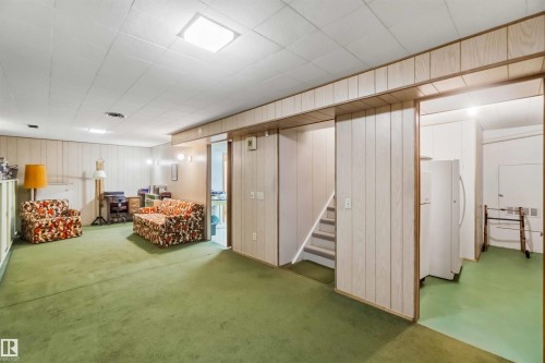 Recessed ceiling lighting, paneled walls, green floor, and built-in staircase - 9311 68 Street Nw, Edmonton, AB 