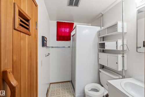 Wood-paneled sauna door with slatted window, built-in shelving, white toilet, and enclosed shower - 9311 68 Street Nw, Edmonton, AB 