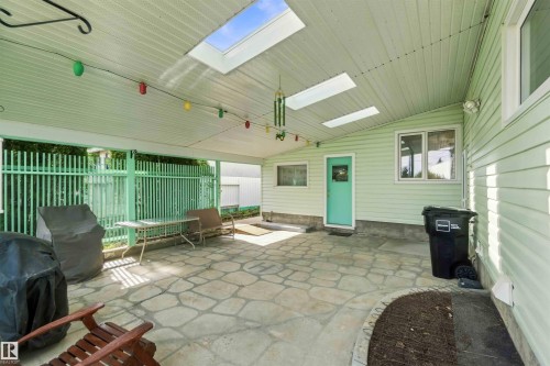 Covered patio with multiple skylights, stone tile flooring, and light green exterior siding - 9311 68 Street Nw, Edmonton, AB 